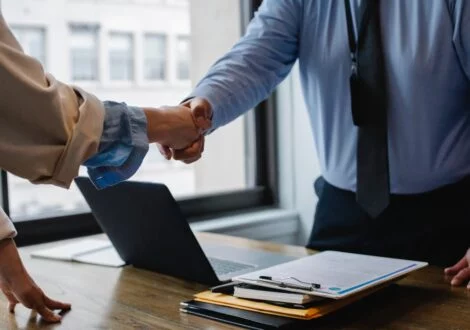Verslo partneriai spaudžia rankas prie darbo stalo